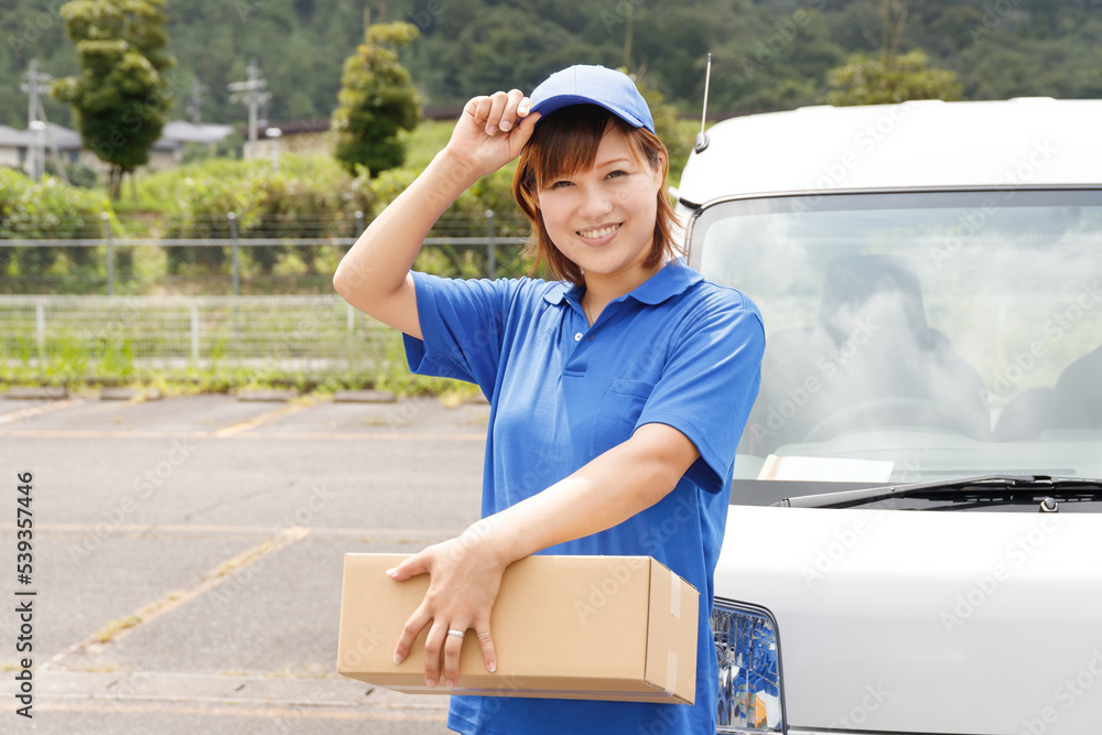 引越しや軽貨物ドライバーなど物流関係の仕事をする女性が笑顔で挨拶をする。青いポロシャツと帽子のユニフォーム。 引越しや軽貨物ドライバーなど物流関係の仕事をする女性が笑顔で挨拶をする。青いポロシャツと帽子のユニフォーム。