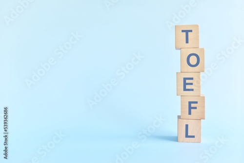 Obraz na płótnie TOEFL or test of english as a foreign language testing system exam concept. Wooden blocks typography flat lay on blue background. w salonie