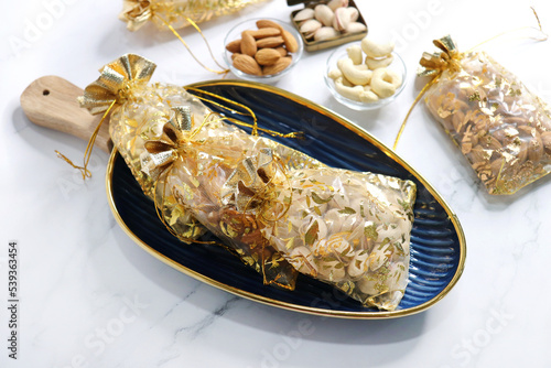 Diwali celebration. Beautiful gifts with traditional design bags containing dry fruits. Cashew, pistachio, and almond. Assorted Dry fruits packed for gift in festivals. Healthy snacking. copy space photo