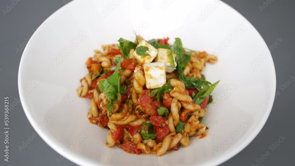 Feta pasta salad with rocket and tomatoes on a white plate Feta pasta salad with rocket and tomatoes on a white plate