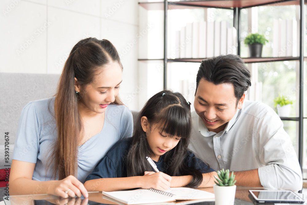 Happy daughter sitting and doing her homework relaxing with her father and mother family at home. Happy daughter sitting and doing her homework relaxing with her father and mother family at home.