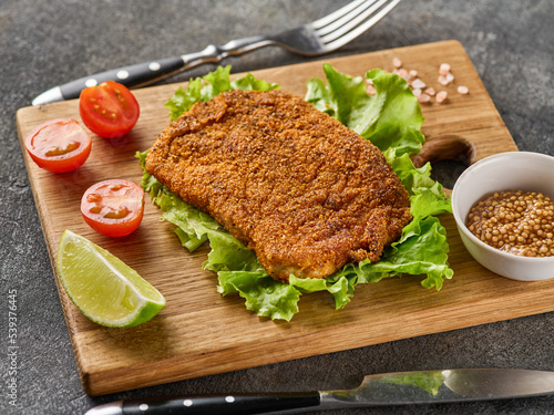 Billede på lærred Breaded pork cutlet with cherry tomatoes, mustard and lemon.