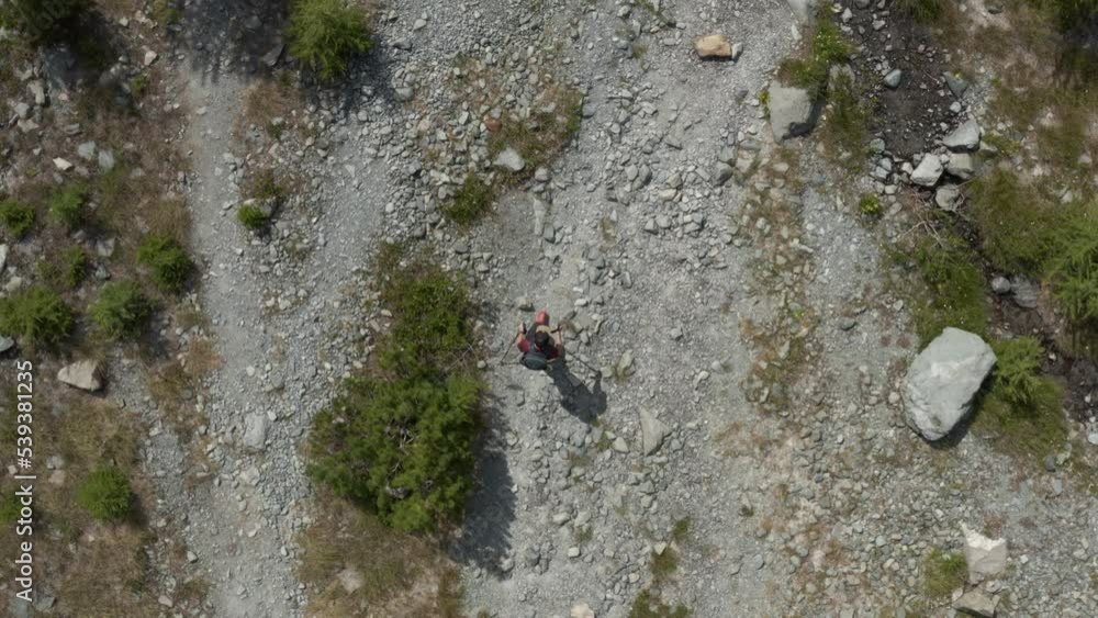 Aerial view of one person hiking with sticks and backpack in the beautiful landscape of the Alpe Ventina in Chiesa in Valmalenco, Lombardy, Italy. Aerial view of one person hiking with sticks and backpack in the beautiful landscape of the Alpe Ventina in Chiesa in Valmalenco, Lombardy, Italy.