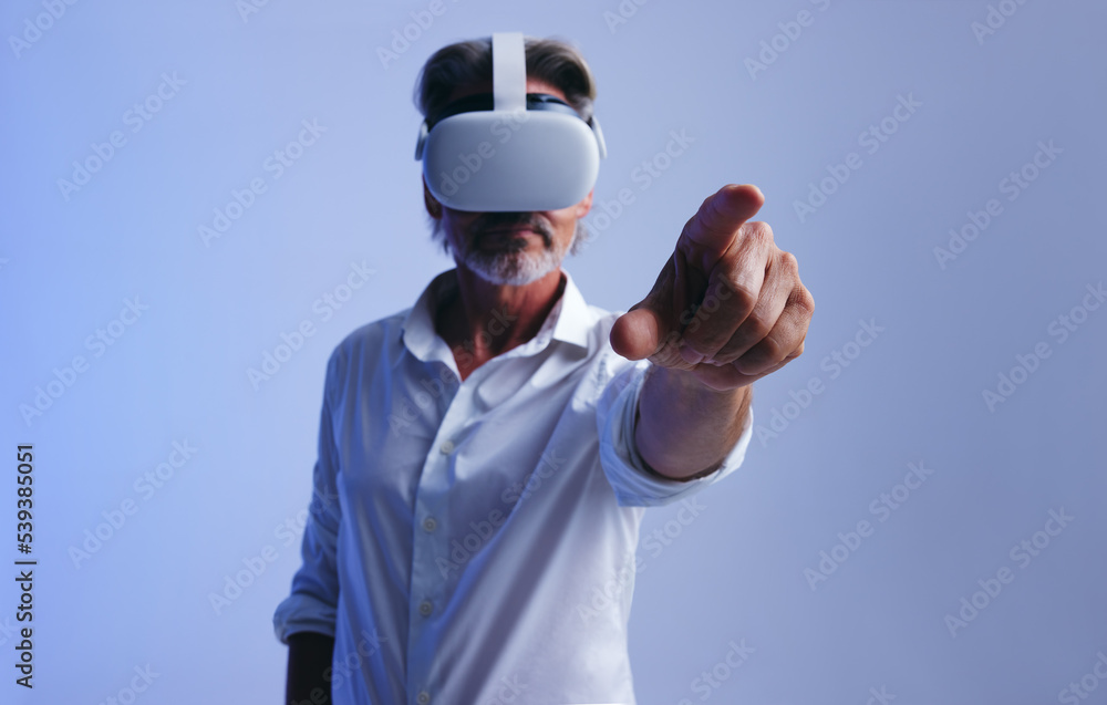 Businessman interacting with virtual space in a studio. Senior business man wearing a virtual reality headset Businessman interacting with virtual space in a studio. Senior business man wearing a virtual reality headset