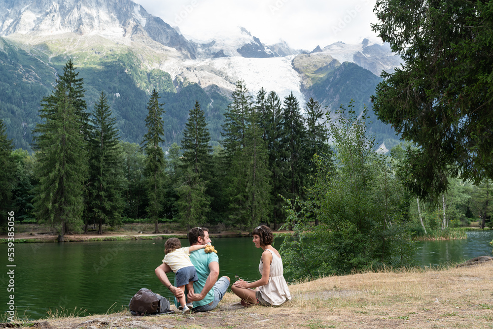 Family with one toddler playing at Gaillands lakeshore with  views at  Mont Blanc and glacier of bossons in Chamonix, french alps.