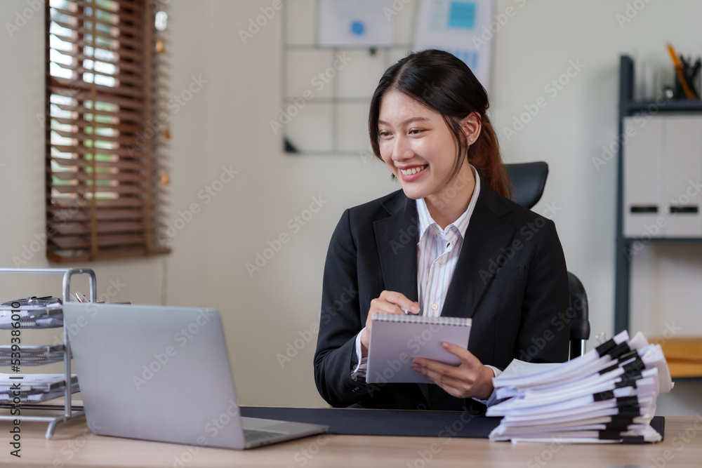 Young Asian businesswoman who is happy to work in the office with a lot of paperwork arranged on the desk. Young Asian businesswoman who is happy to work in the office with a lot of paperwork arranged on the desk.