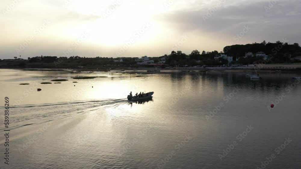 Small Motorboat Sailing On The Tranquil Ria Formosa Lagoon At Sunset In Portugal - aerial drone shot Small Motorboat Sailing On The Tranquil Ria Formosa Lagoon At Sunset In Portugal - aerial drone shot
