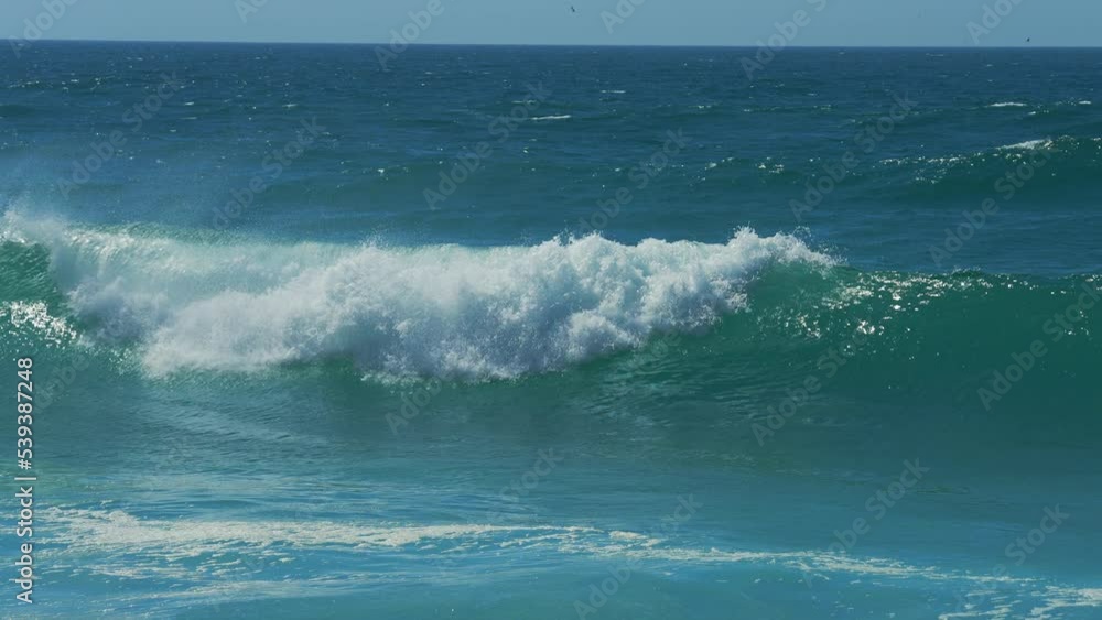 Close-up slow motion shot of sea waves breaking on sandy coastline in Portugal Close-up slow motion shot of sea waves breaking on sandy coastline in Portugal