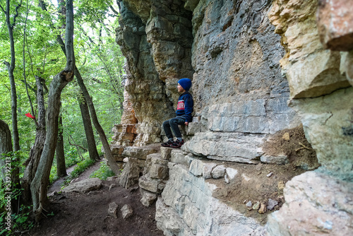 A little boy on the background of rocks in a picturesque forest on the way to the eagle shelf. Mezmai 2021 © Виктория Балобанова