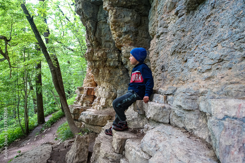 A little boy on the background of rocks in a picturesque forest on the way to the eagle shelf. Mezmai 2021