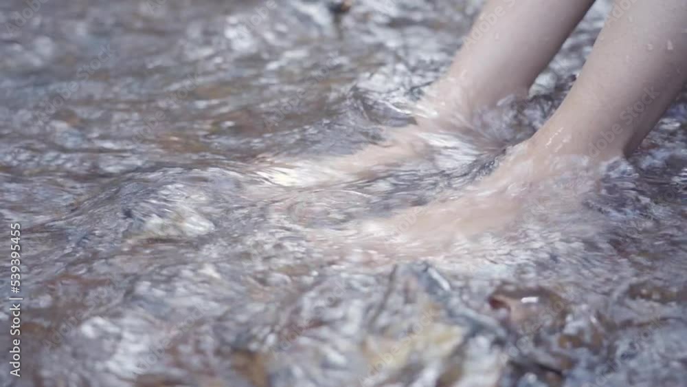 Woman's feet under water in a natural water stream in slow motion Woman's feet under water in a natural water stream in slow motion