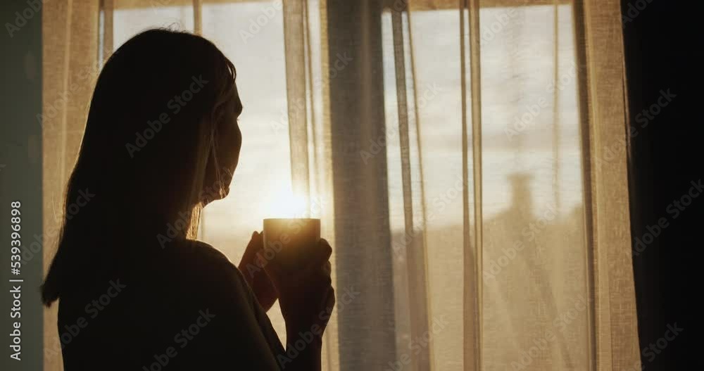 Middle aged Woman With A Cup Of Tea In Her Hands Looking Out The