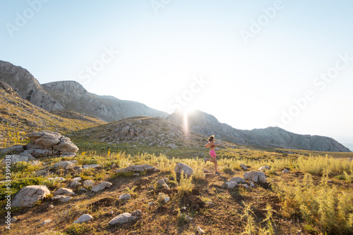 Runner woman running through beautiful mountains
