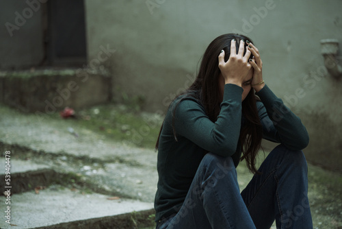 Helpless, hurt, depressed young woman feeling completely crushed, sitting outside on a cold day, grieving her fate