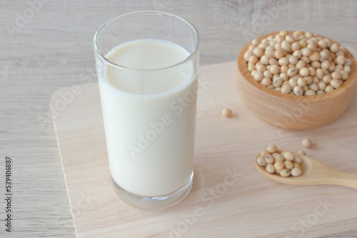 Glass of soy milk and soy beans in a bowl and spoon on wooden background.