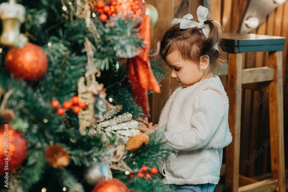 girl child kid is decorating a Christmas tree.