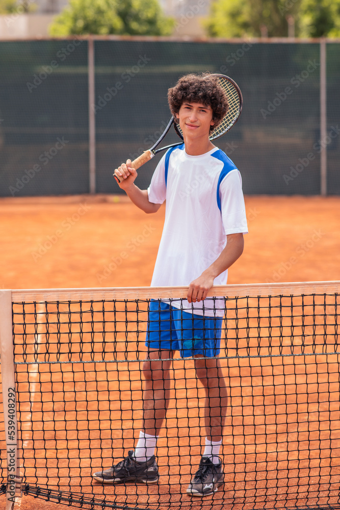 Good looking charismatic young man posing in front of the camera professional tennis player in uniform he holding the tennis racket in hands Good looking charismatic young man posing in front of the camera professional tennis player in uniform he holding the tennis racket in hands