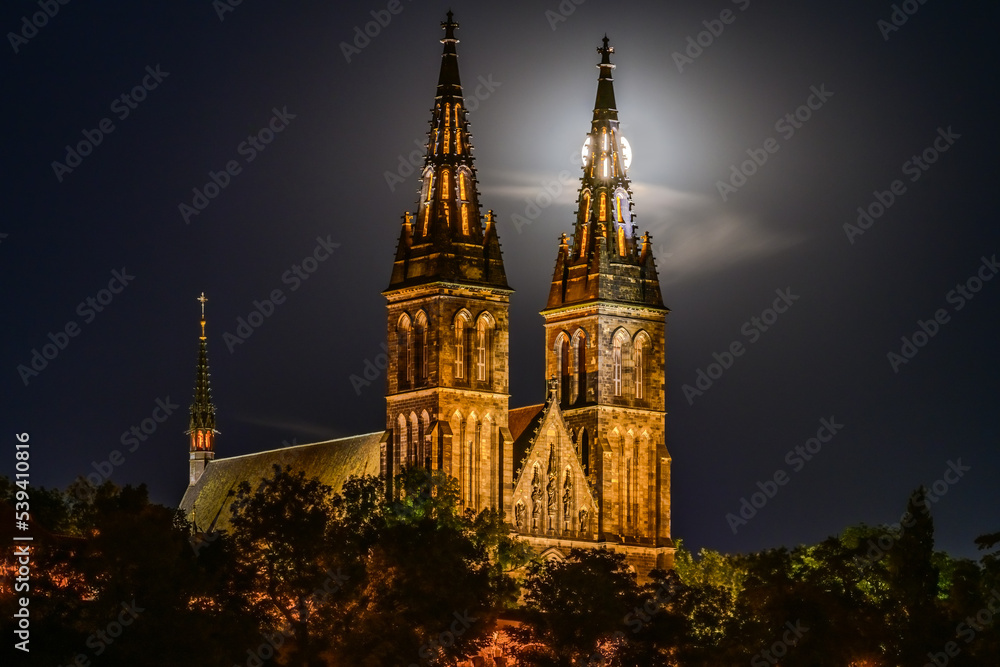Full moon over the illuminated Basilica of St. Peter and St. Paul on Vysehrad hill in Prague.