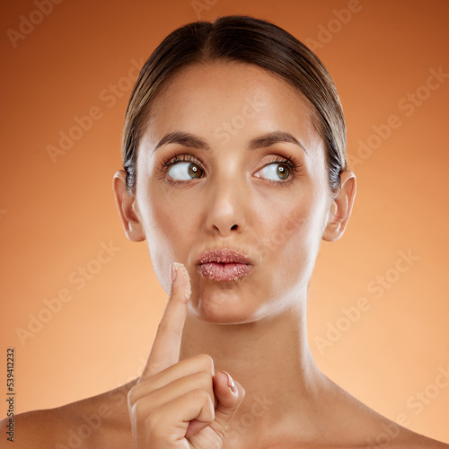 Woman with sugar scrub on lips, skincare with natural product or handmade wellness treatment in studio. Girl thinking on orange background, exfoliate mouth with peeling smooth skin for beauty idea