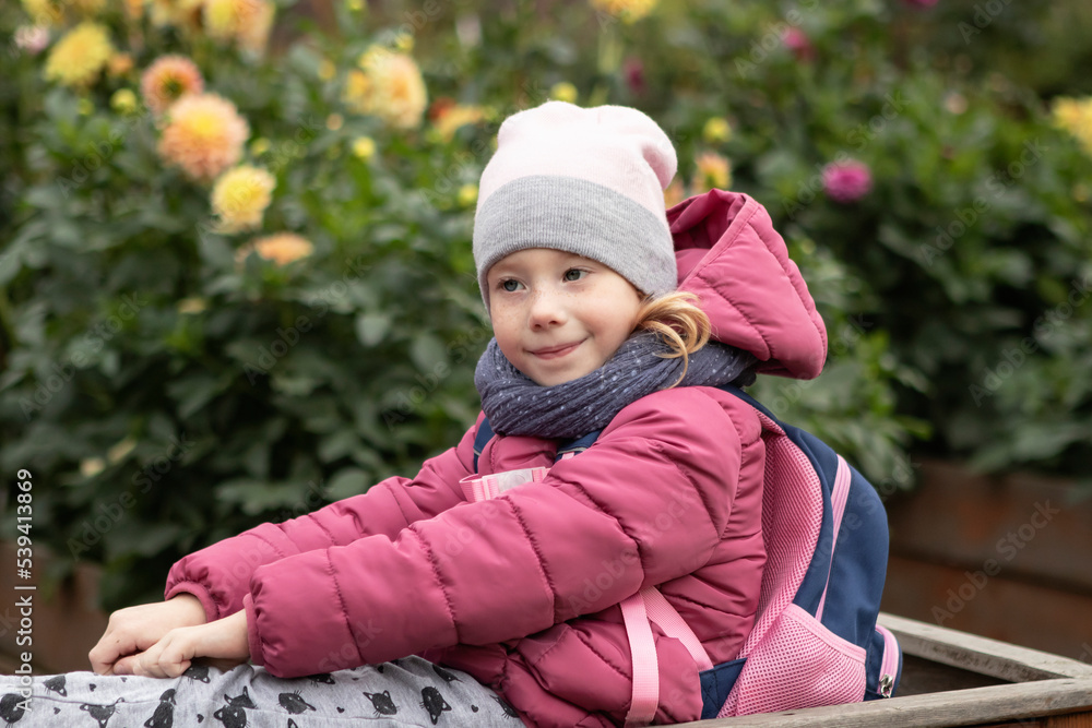 girl in a pink jacket and a hat for a walk in the park among the flowers in autumn girl in a pink jacket and a hat for a walk in the park among the flowers in autumn