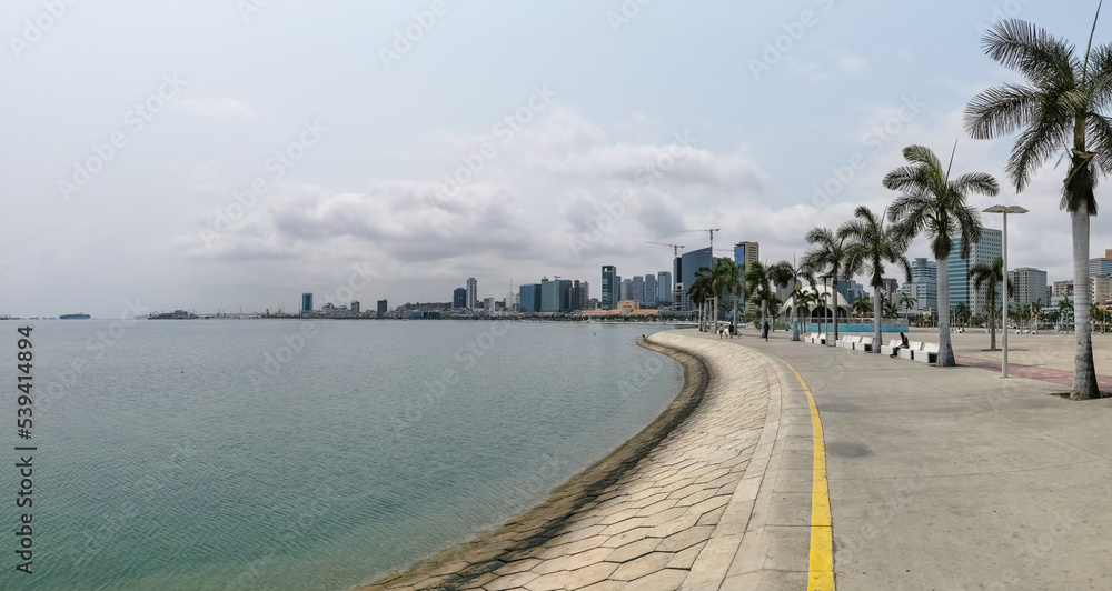 Panoramic view at the Luanda bay and Luanda marginal, pedestrian pathway with tropical palm trees, downtown lifestyle, Cabo Island, Port of Luanda and modern skyscrapers