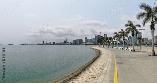 Panoramic view at the Luanda bay and Luanda marginal, pedestrian pathway with tropical palm trees, downtown lifestyle, Cabo Island, Port of Luanda and modern skyscrapers