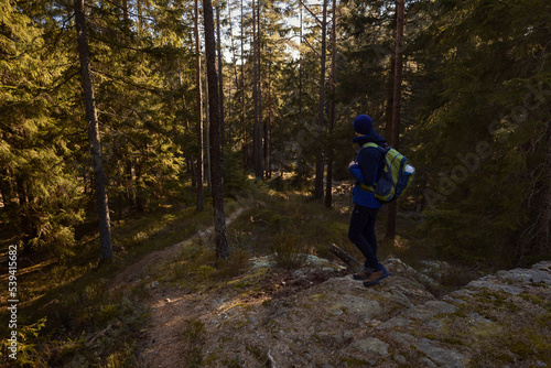 A man with a backpack standing in a forest at sunrise.