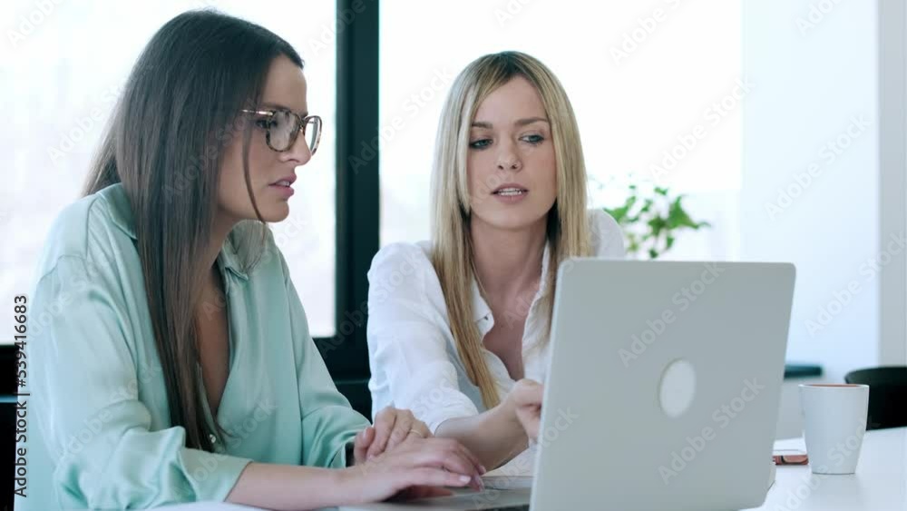 Video of two business women working together with laptop while talking about work in the office Video of two business women working together with laptop while talking about work in the office