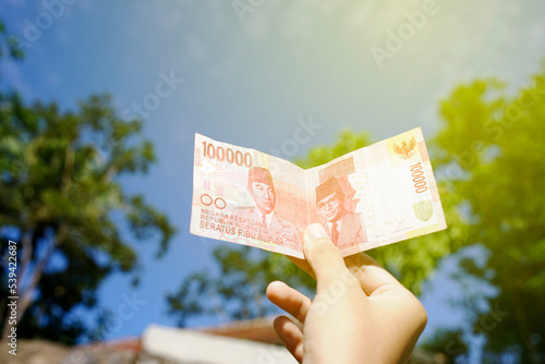 the woman hands over one hundred thousand. Indonesian currency with a blur background