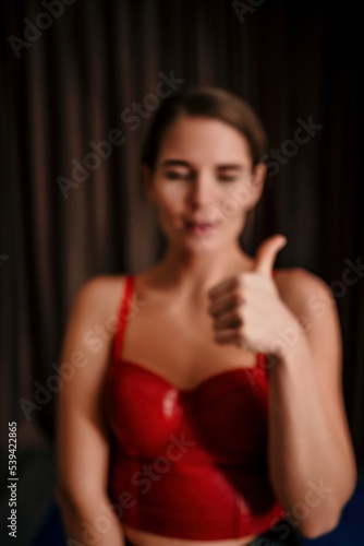 Defocused and Blured Abstract Photo Young woman in red corset and black leather pants. Sexy brunette in red and black costume. Role play. Entertainment. Perfect for background. © panophotograph