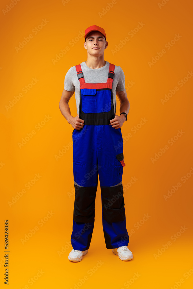 Full length shot of a young male worker in uniform on yellow background Full length shot of a young male worker in uniform on yellow background