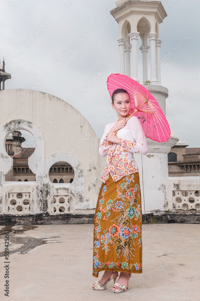 Fashion portrait photo of a beautiful elegant young asian female lady model wearing traditional baba-nyonya peranakan culture kebaya garment dress with sarong posing with different looks and gesture