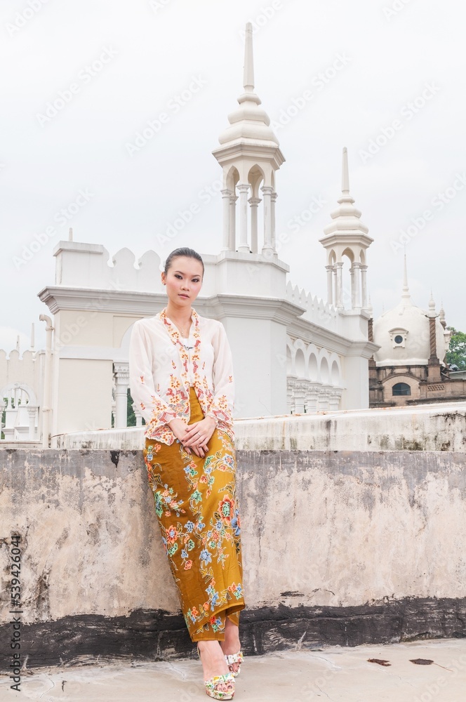 Obraz premium Fashion portrait photo of a beautiful elegant young asian female lady model wearing traditional baba-nyonya peranakan culture kebaya garment dress with sarong posing with different looks and gesture