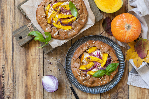 Homemade galette pie or crostata with pumpkin and ricotta cheese on rustic background. Thanksgiving day food. View from above. Copy space.