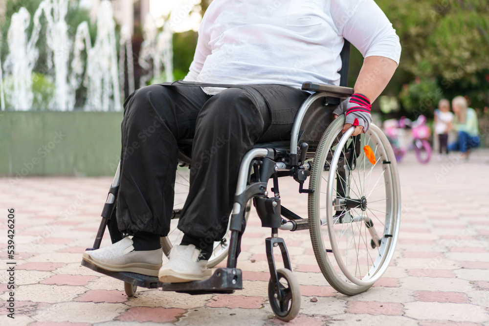 Obraz premium Unrecognizable woman with disability sitting in wheelchair in the street close up