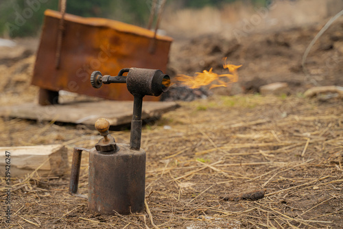 Hand gas burner with yellow flame on wooden background