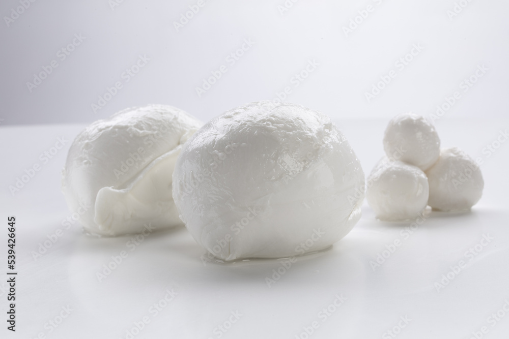 Whole mozzarella with morsels of fresh mozzarella on a white background