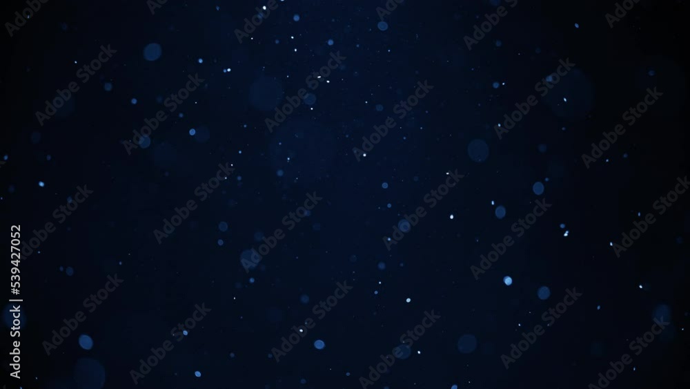 Blue dust bokeh particles floating in the air. Slow motion. 