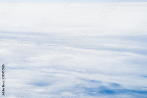 Flying Above the Clouds with Blue Skies in an Airplane Looking out of the Window. White fluffy clouds below with the darkness of space. Beautiful white clouds.