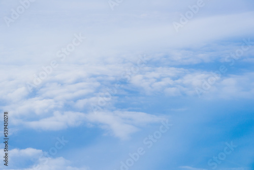 Fototapeta Naklejka Na Ścianę i Meble -  Flying Above the Clouds with Blue Skies in an Airplane Looking out of the Window. White fluffy clouds below with the darkness of space. Beautiful white clouds.