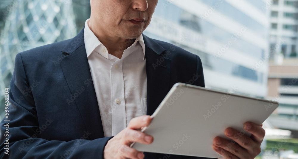 An Anonymous Asian Businessman Working On A Digital Tablet In The City An Anonymous Asian Businessman Working On A Digital Tablet In The City