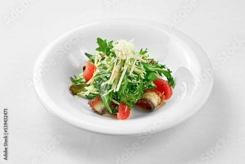 Salad with eel and grapefruit on a white plate against a white background. Close-up, selective focus