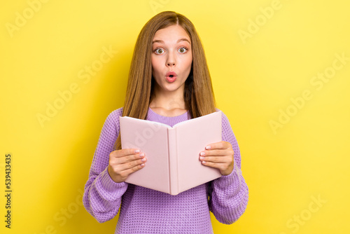 Photo of astonished clever lady wear trendy clothes hand hold textbook impressed interesting plot isolated on yellow color background