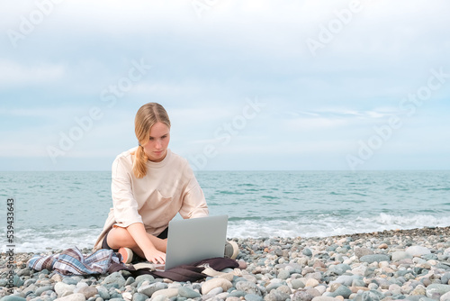 Remote work.Girl freelancer works remotely on the sea shore. workation, remote work,WFVH,Van Life vibes work from vacation home,work travel,remotely work.Travelling.Work from vacation remotely © shintartanya