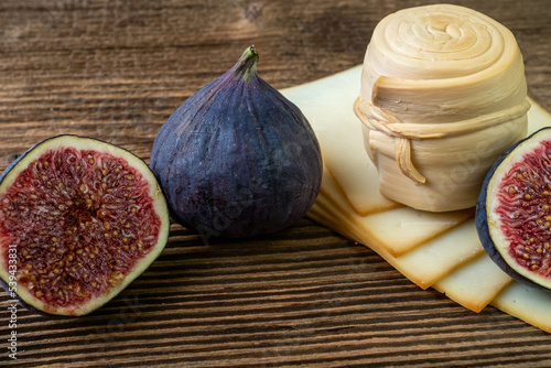 Figs, various cheese on a rustic table.Traditional hand made slovak smoked cheese parenica. Healthy eating concept. photo