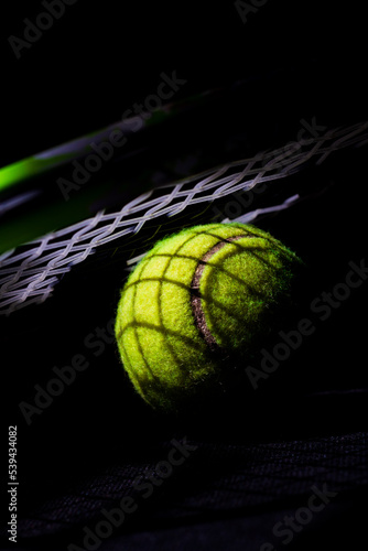 Tennis racket on tennis ball with strong contrast chiaroscuro light effect with dark shadows © Mandy Short