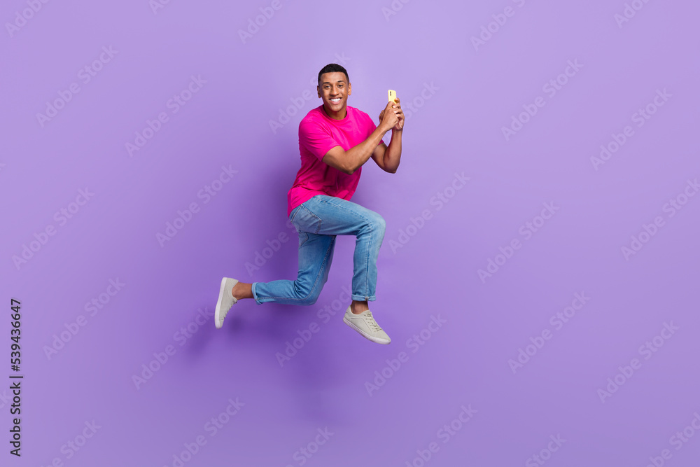 Full size profile portrait of active handsome guy jumping rush hold use telephone isolated on purple color background Full size profile portrait of active handsome guy jumping rush hold use telephone isolated on purple color background
