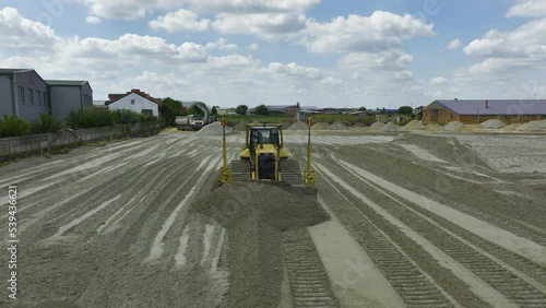 Front, view of large bulldozer or crawler with GPS moving sand at construction site.