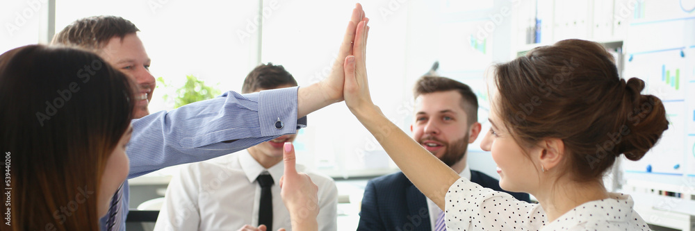 Colleagues give high five gesture in order to celebrate end of company project Colleagues give high five gesture in order to celebrate end of company project