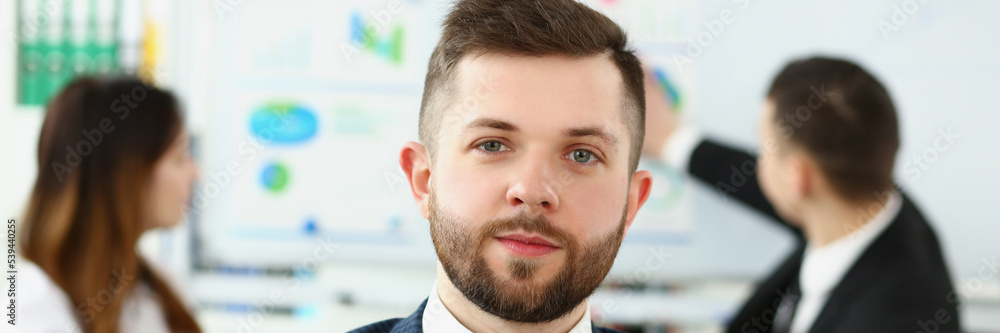 Obraz premium Businessman in office in presentable suit, colleagues on background near board